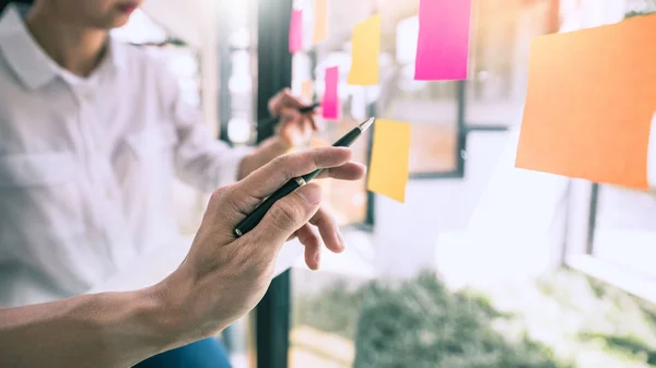 La gente de negocios se reúne en la oficina y usa notas adhesivas en el vidrio — Foto de Stock