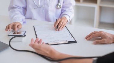 Bir hastaya kan basıncını ölçmek için sphygmomanometre ya da tonometre kullanan doktor kalp atışlarını inceledi ve hastanedeki sağlık hizmetlerinden bahsetti.