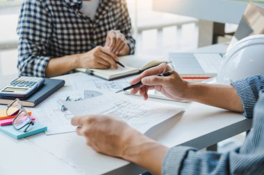Mühendis El Çizimi Mavi Yazdırma Planı. Mimari ekipmanlarla birlikte modern bir ofiste, mimari planlar üzerinde kat planlarını tartışıyorlar.