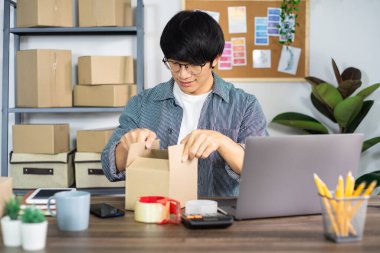 Karton kutuda çalışan Asyalı işadamı KOBİ girişimcisi veya serbest çalışan girişimci müşteri, çevrimiçi satış, e-ticaret, ambalaj ve nakliye kavramı için teslimat kutusu hazırlar