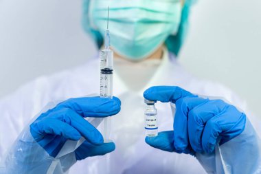 Doktor, bilim adamı, mavi eldivenli bir araştırmacı ya da koruyucu giysi giymiş. İnsan klinik enjeksiyon deneylerine hazırlanıyor. Cvid-19 Coronavirus aşısı biyolojik tehlike kavramı.