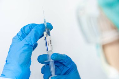 Doktor, bilim adamı, mavi eldivenli bir araştırmacı ya da koruyucu giysi giymiş. İnsan klinik enjeksiyon deneylerine hazırlanıyor. Cvid-19 Coronavirus aşısı biyolojik tehlike kavramı.
