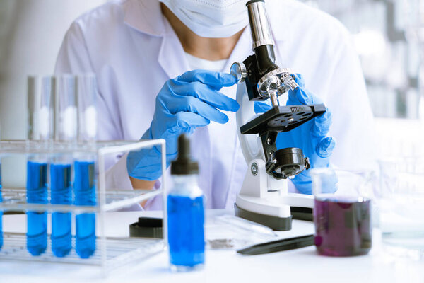 Молодой азиатский ученый, изучающий микроскоп, изучающий образец эксперимента в судебно-медицинской лаборатории