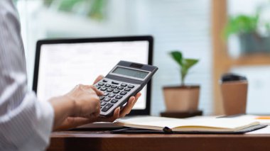 Muhasebe işi kavramı, bürodaki hesap makinesini kullanarak evrak işi yapan iş adamı ve dizüstü bilgisayara güvenen finansal veri analizi..