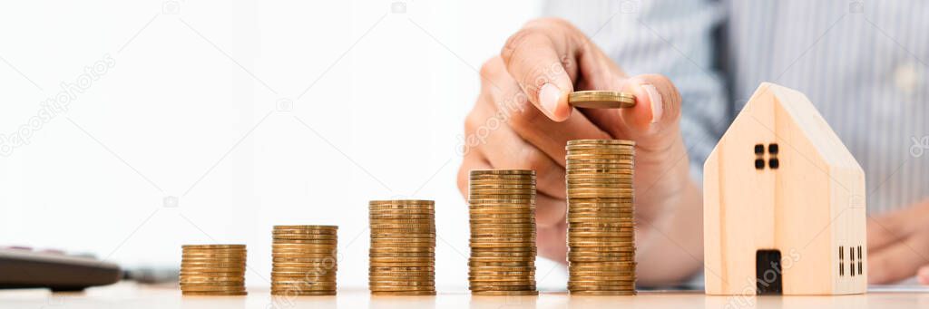 Property investment and house mortgage financial concept, hand of a businessman who is stacking coins for Real estate investment, saving for buying for housing or speculation