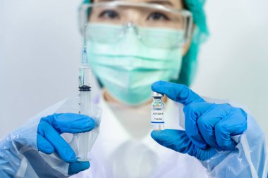 Doktor, bilim adamı, mavi eldivenli bir araştırmacı ya da koruyucu giysi giymiş. İnsan klinik enjeksiyon deneylerine hazırlanıyor. Cvid-19 Coronavirus aşısı biyolojik tehlike kavramı.
