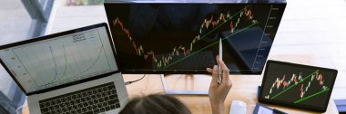 Grafiklerle çalışan borsa simsarı, modern ticaret ofisindeki monitörde şemalar var..