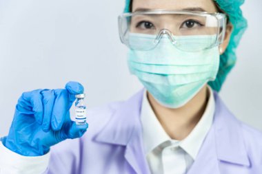 Coronavirus aşısı COVID-19 şişesi koruyucu giysi içinde doktor veya teknisyen bilim adamı, antiviral sağlık ve tıbbi biyolojik tehlike konsepti.