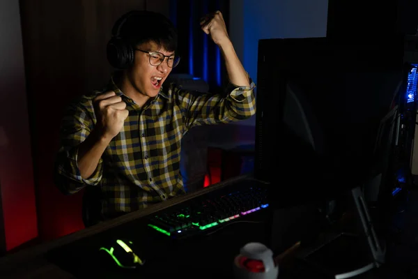 兴奋的亚裔男子职业玩家坐在桌旁 用计算机和智能手机 技术游戏 网络游戏或电子竞技锦标赛的概念玩在线游戏并赢得比赛 — 图库照片