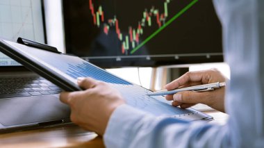 Grafiklerle çalışan borsa simsarı, modern ticaret ofisindeki monitörde şemalar var..