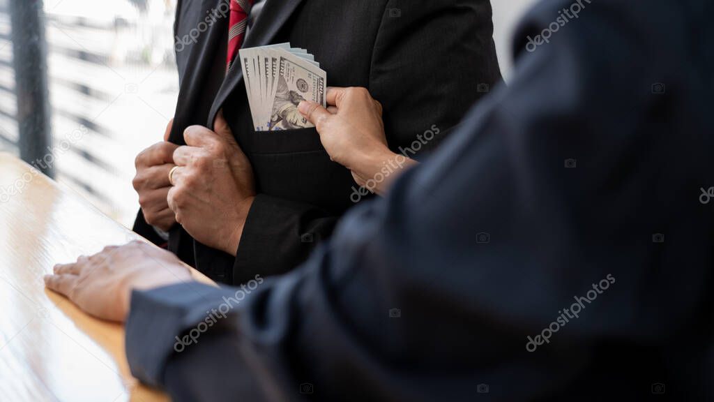 Businessman reciving money United States Dollars bills to corruption from his partner in business at working desk - bribery concept