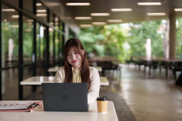 Взрослая азиатка с удовольствием занимается внештатной удаленной работой на открытом воздухе. Наслаждение продуктивным гибким образом жизни в естественной среде.