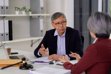 Asian legal professional and client engage in serious discussion Expert advice provided during important office meeting Collaborative problem solving
