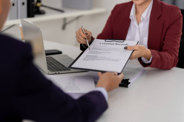 Legal professional and client review criminal records document during an office consultation. Pen pointing to key points for discussion.