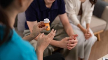 Caring healthcare provider discusses medication with adult patients during a private home visit. Expert offers personalized medical advice for wellness journey.