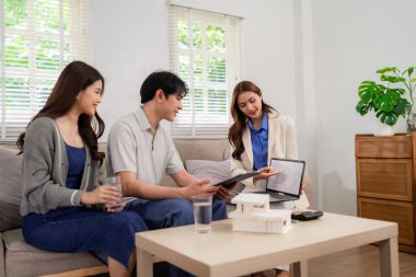 Asian real estate agent meets adult couple at home presenting property options financial planning investment strategies secure future