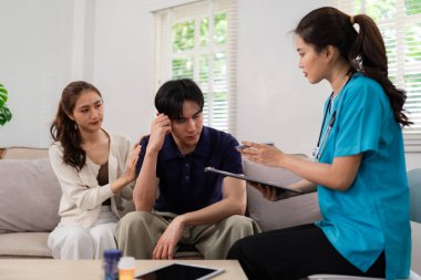 Healthcare professional offers compassionate at home mental health support to worried Asian couple seeking counseling and medical guidance.