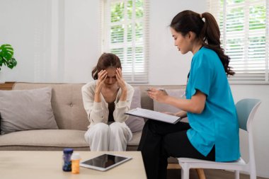 Empathetic Asian woman doctor provides private mental health consultation to adult patient experiencing stress depression at home offering support wellbeing counseling.