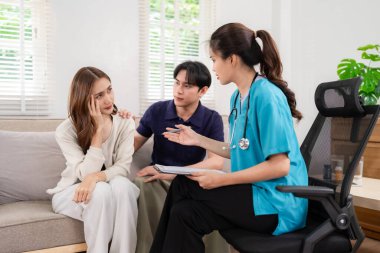 Expert Asian doctor offers private mental health consultation to an adult couple at their residence providing compassionate support and guidance for wellbeing concerns
