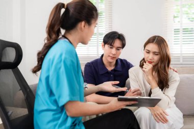 Professional Asian physician offers empathic mental health guidance to adult couple in comfortable home environment fostering understanding and support