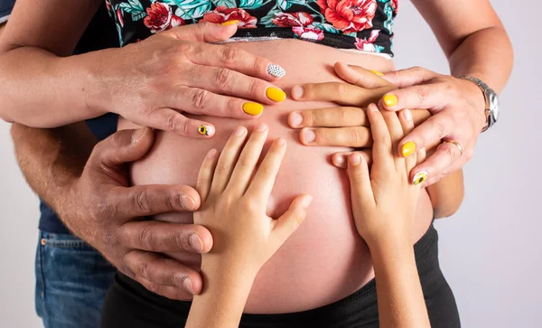 Anne, baba ve oğlu elleriyle hamile kadının göbek