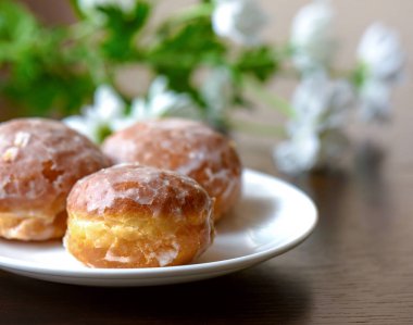 Masanın üzerine çiçek ile beyaz tabakta donut