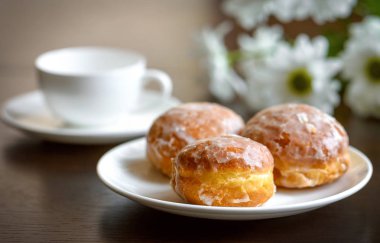 Masanın üzerine çiçek ile beyaz tabakta donut