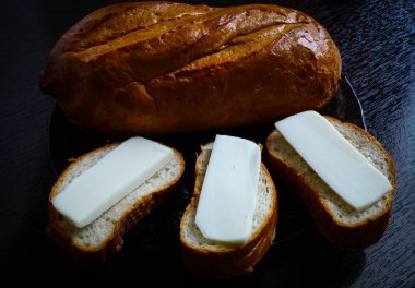 Altın kahverengi kabuklu taze bir somun. Cam tabakta sandviçler, üç dilim. Taze beyaz ekmek ve eritilmiş peynir ile Kahvaltı sandviç