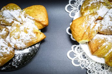 Elma reçelli çörekler tabakta. Yuvarlak, üzerine şeker serpilmiş.