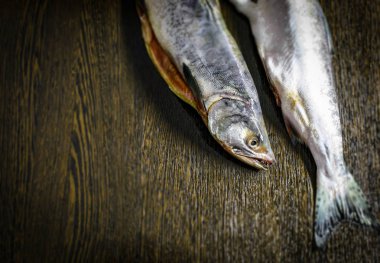 Kahverengi bir masada taze donmuş iki pembe somon.