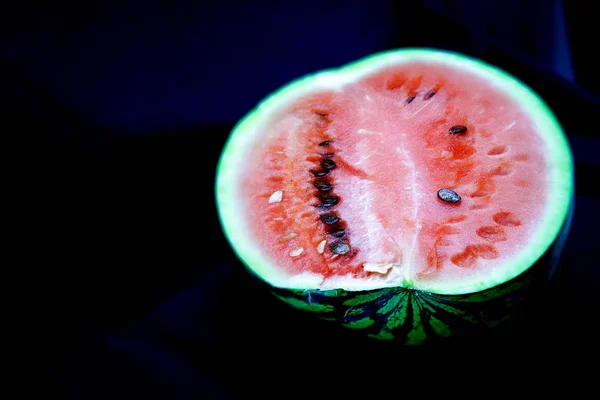 The horizontal photo shows the image of a fresh watermelon, cut in half, with a juicy pink flesh, a small number of seeds