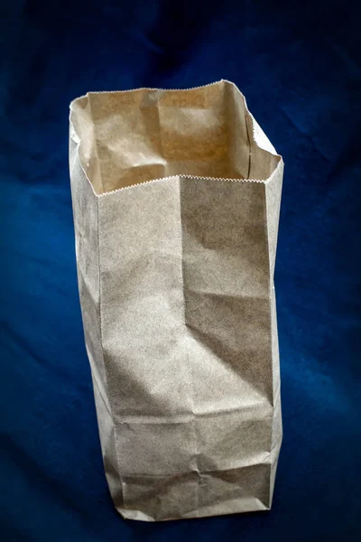 Paper bag open, empty on blue background. In the package was stored the food, bought in a store