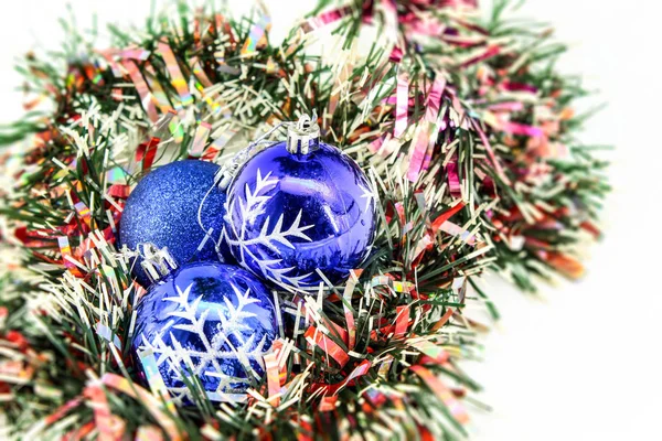 In the horizontal photo, a white background on which Christmas decorations are presented, among which, three blue toy balls to decorate the Christmas tree in the house, on the street, in the yard, at school, in kindergarten and in other institutions