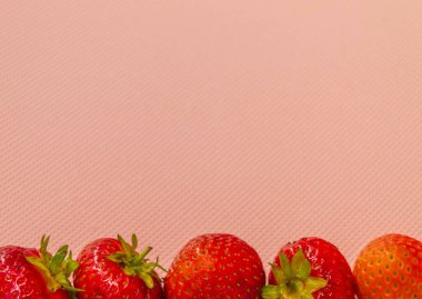 Pembe arka planda beş sulu kırmızı çilek var.