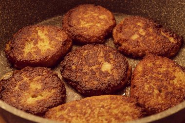 Fotoğrafta tavada yemek var. Yedi kızarmış patates köftesi, soğan, bir yumurta, buğday unlu.