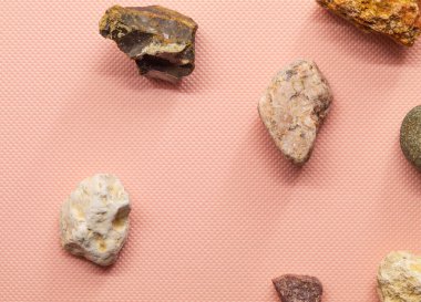 Pembe arka plandaki yatay fotoğrafta az sayıda taş var. Farklı renkte, farklı şekillerde. Sokaktan taşlar.