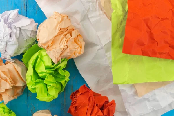 View from above on crumpled and crumpled paper, which has different colors: white, red, lettuce, orange. There are crumpled straightened sheets, also heavily crumpled