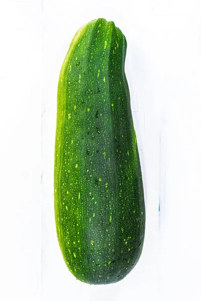 Uma grande courgette vegetal de cor verde está em um fundo branco — Fotografia de Stock