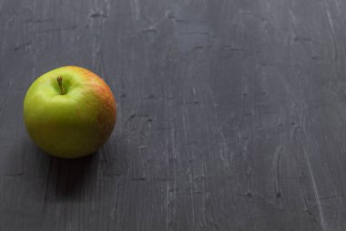 Kenarında siyah bir arka planda duran küçük taze bir elma.