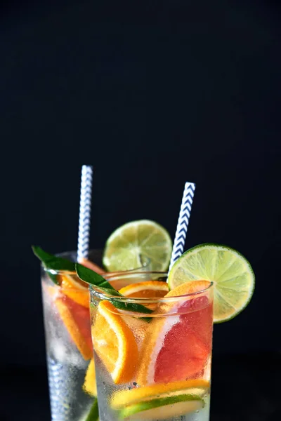 Health care, fitness, healthy nutrition diet concept. Fresh cool homemade citrus infused detox water with grapefruit, orange, lemon and lime and ice in glasses on dark background.