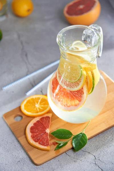Health care, fitness, healthy nutrition diet concept. Fresh cool homemade citrus infused detox water with grapefruit, orange, lemon and lime and ice in a jug and glasses for spring summer days.