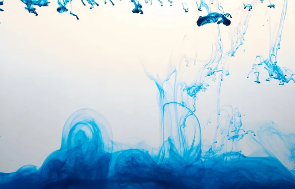 Closeup of a blue ink in water in motion isolated on white. Ink swirling underwater. Colored abstract smoke explosion effect. Abstract background with copy space..