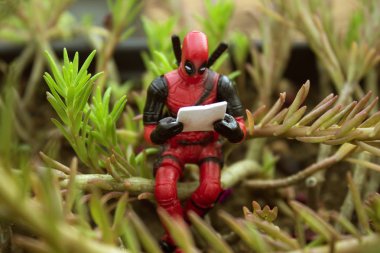 Rio de Janeiro, Brezilya, 25 Kasım 2018: Deadpool bitki üzerinde oturan Minifigure. Bitki altında bir gazete okuyor Deadpool.