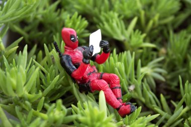 Rio de Janeiro, Brezilya, 25 Kasım 2018: Deadpool bitki üzerinde oturan Minifigure. Bitki altında bir gazete okuyor Deadpool.