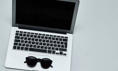Laptop klavyeli şık, minimalist bir iş yeri, düz bir şekilde siyah güneş gözlüğü. Beyaz arka plan. Üst görünüm. 