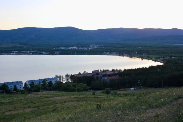 Gün batımında dağlarda dağ gölü olan büyüleyici panoramik bir manzara. Rahatlama, uyum, anti-stres konsepti. Gün batımı