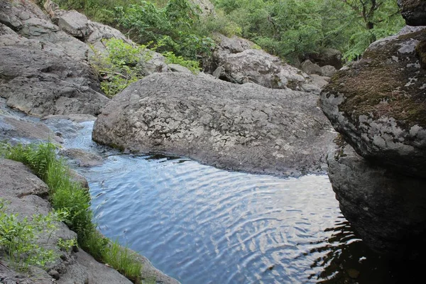 Bergwasserfall. Gebirgsfluss zwischen grauen riesigen Felsbrocken inmitten eines dichten Waldes — Stockfoto