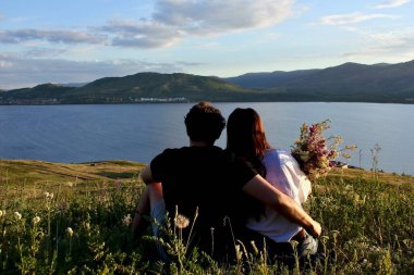 Dağın tepesinde birbirini seven bir çift. Sarıl bana. Gün batımı. Uzun saçlı ve erkek arkadaşı olan genç bir kız. Sevgi. Erkek ve kadın..