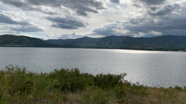 Sommerlandschaft. Dramatischer Himmel. Bergsee. Schöne verschwommene Hintergrund. Eine große grüne Wiese mit Bäumen und Bergen im Hintergrund. Ein Gewässer mit einem Berg im Hintergrund — Stockvideo