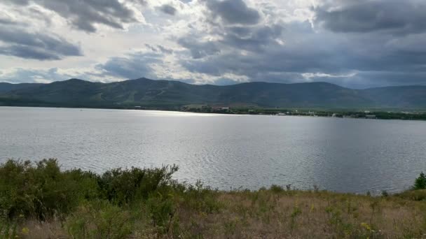 Sommerlandschaft. Dramatischer Himmel. Bergsee. Schöne verschwommene Hintergrund. Eine große grüne Wiese mit Bäumen und Bergen im Hintergrund. Ein Gewässer mit einem Berg im Hintergrund — Stockvideo